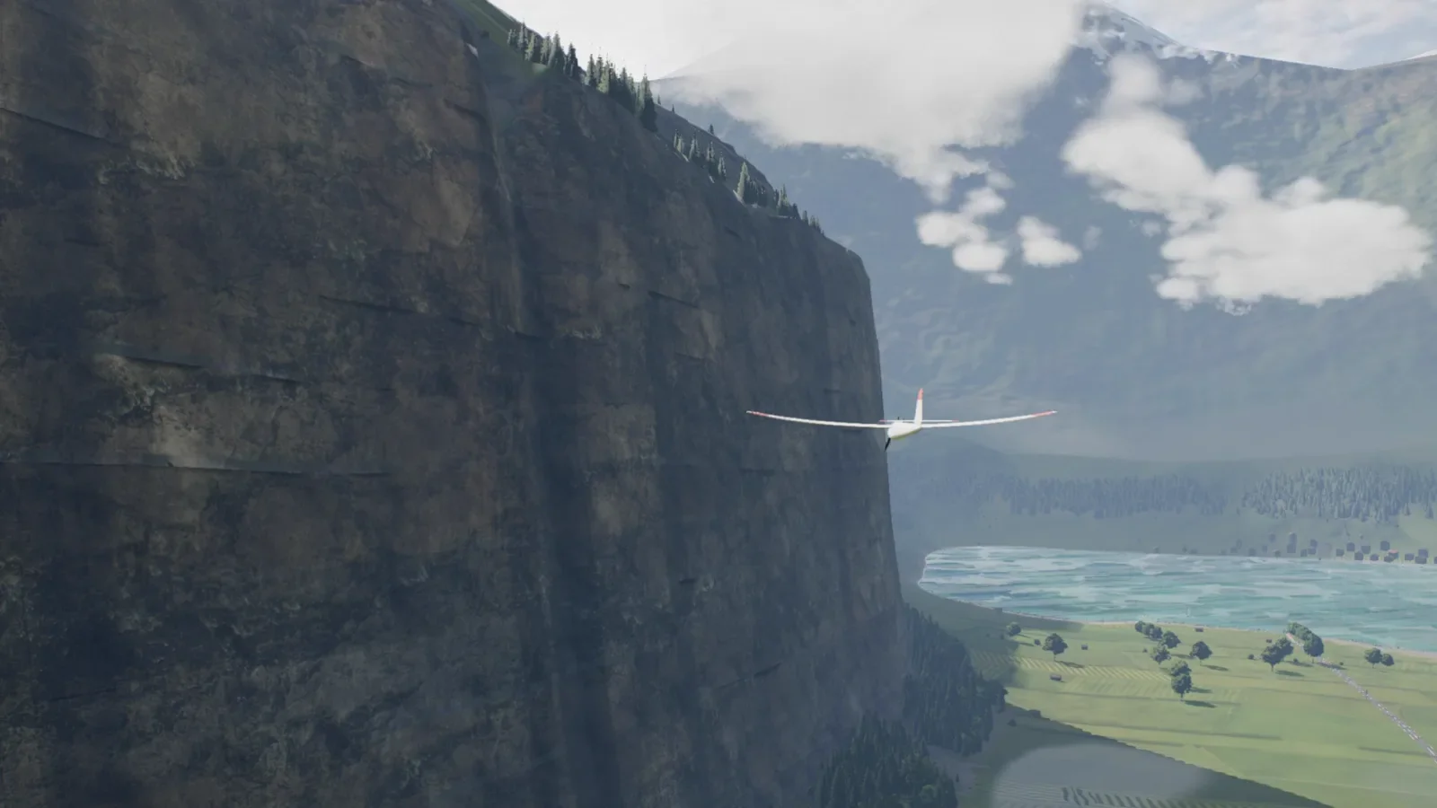An RC motor glider flying down the alpine valley toward its lake, cliffs on the left, rendered in the simulator.